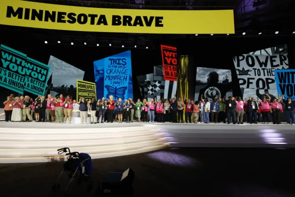 Photo of Minnesota union members on stage at the national AFL-CIO convention with a video wall that reads "Minnesota Brave" overhead.